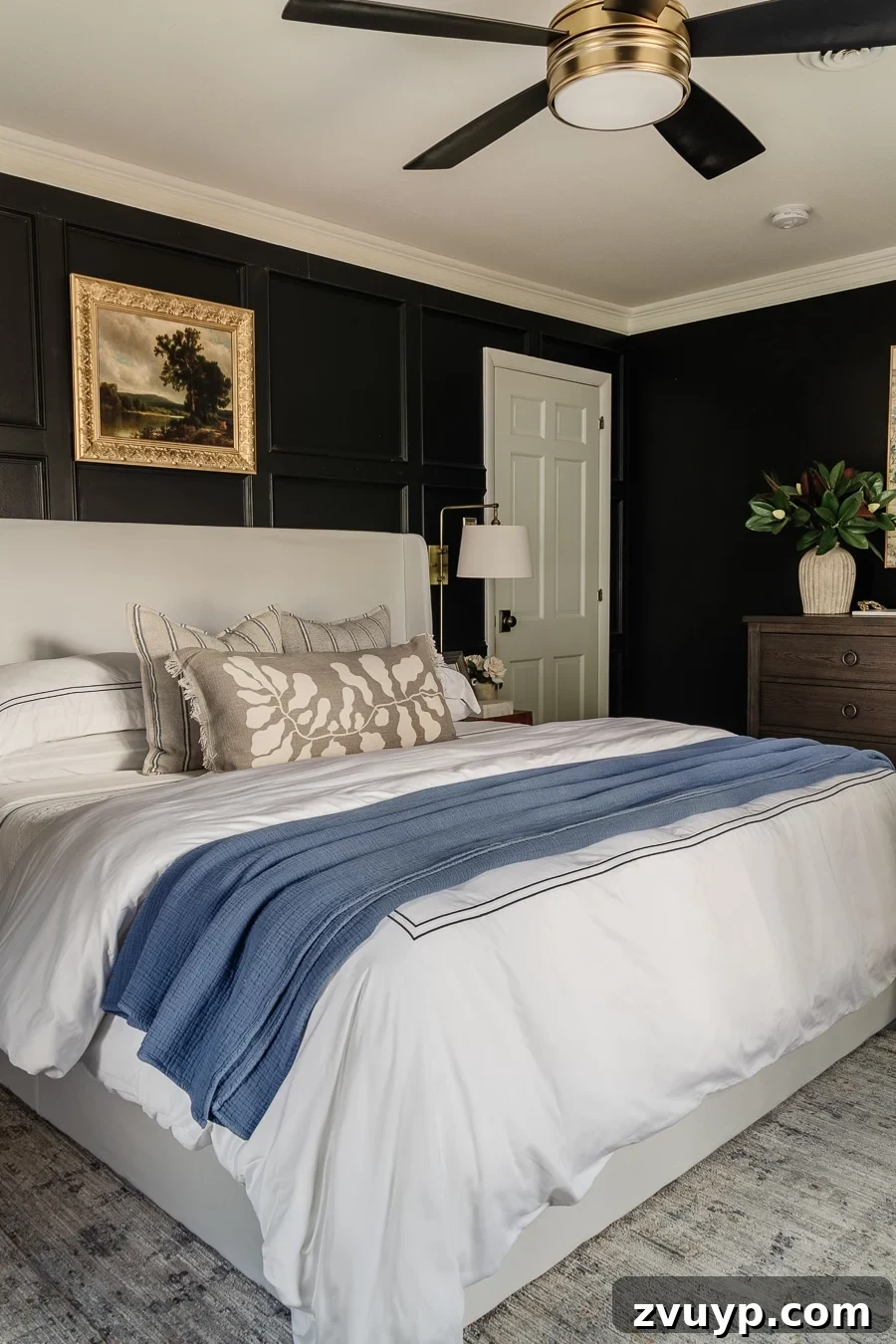 20 Handpicked Modern Ceiling Fans to Adorn Your Home 8 A serene primary bedroom featuring a white wingback storage bed from Amazon, set against a dark wall, with a stylish black and brass ceiling fan.
