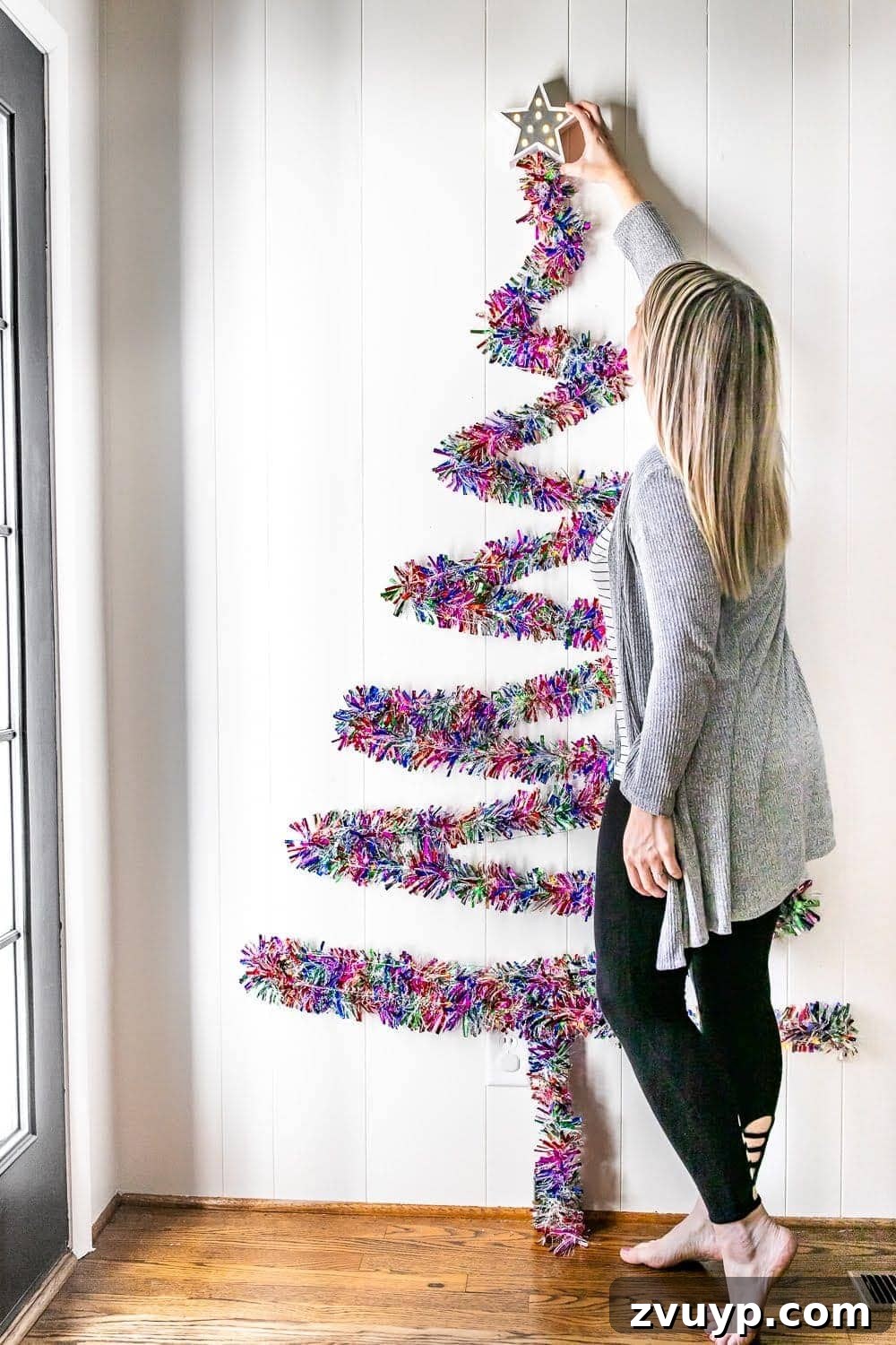 Thrifty Wall Christmas Tree with Twinkling Lights 8 hanging a star on top of garland on a wall