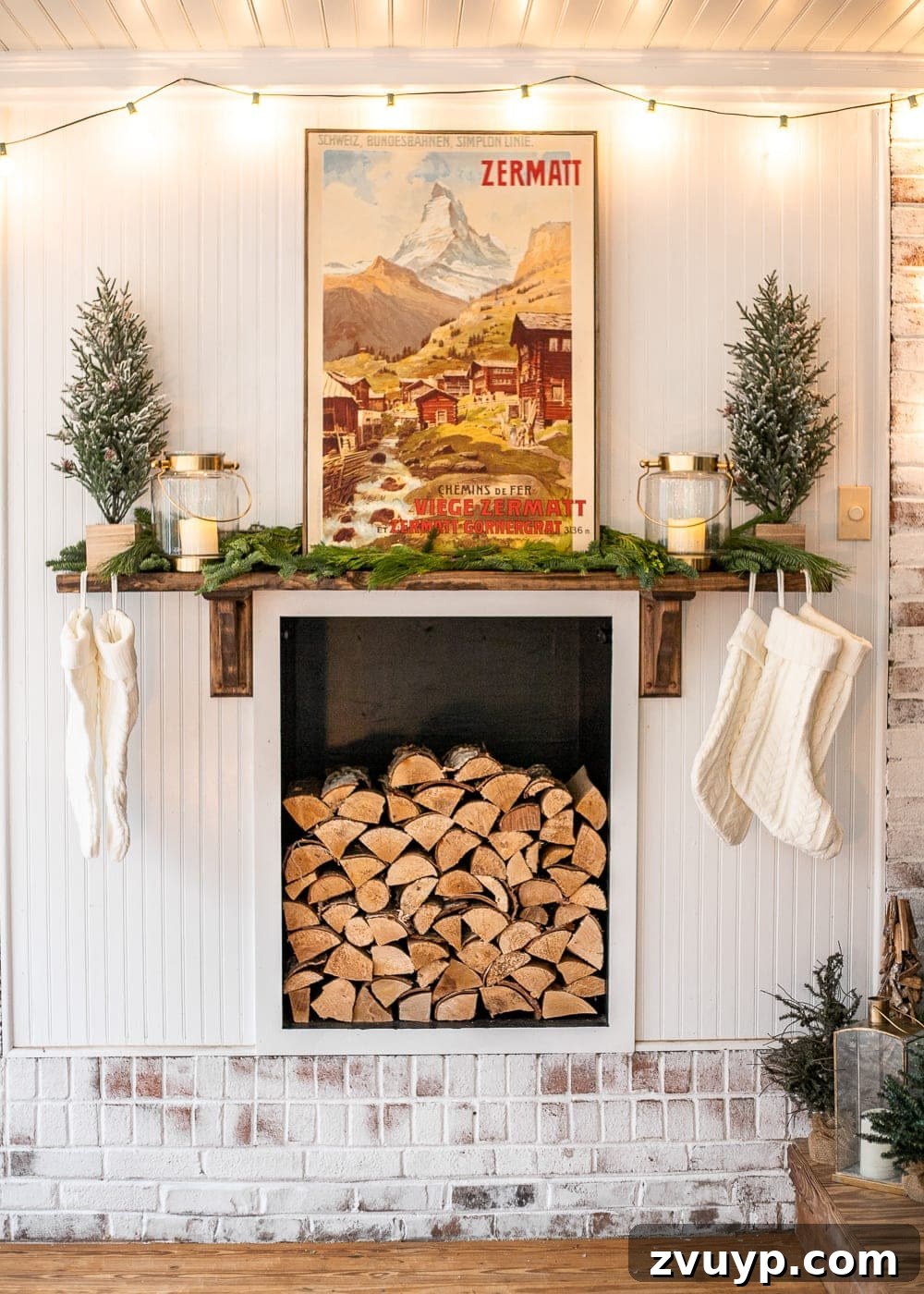 Warm Yuletide Veranda 13 DIY faux fireplace decorated for Christmas with a rustic wood stack, vintage poster art, mini trees, festive stockings, fresh greenery, elegant lanterns, and twinkling string lights