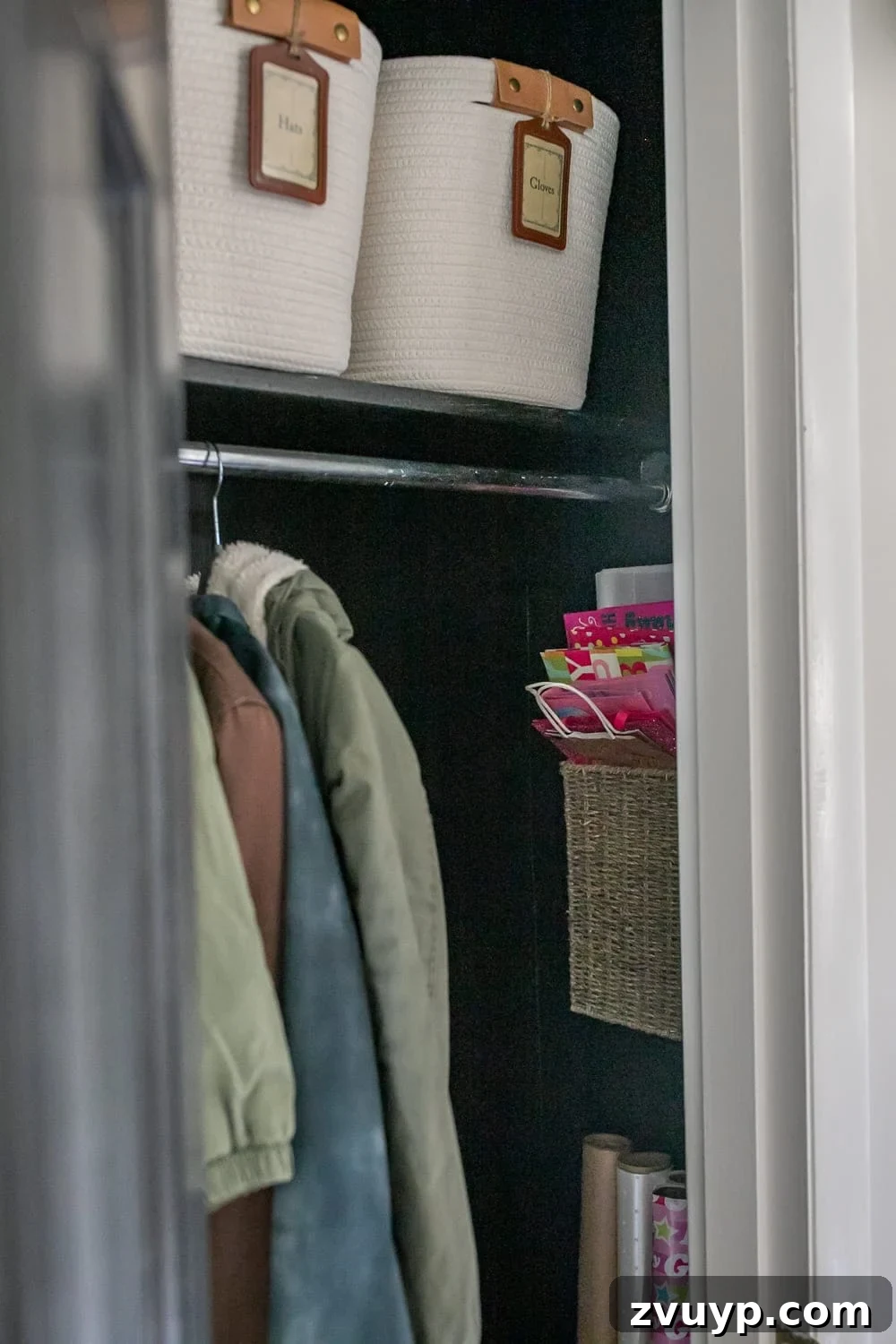 Smart Coat Closet Organization 5 Organized coat closet with dark painted walls, showing a dedicated gift wrap storage area and labeled bins.