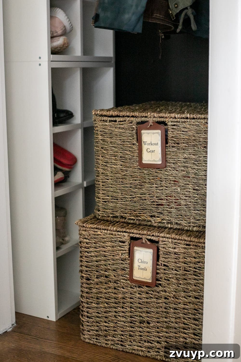 Smart Coat Closet Organization 8 Lidded storage baskets with stylish labels in a coat closet, used for organizing workout gear and other large items on the floor.
