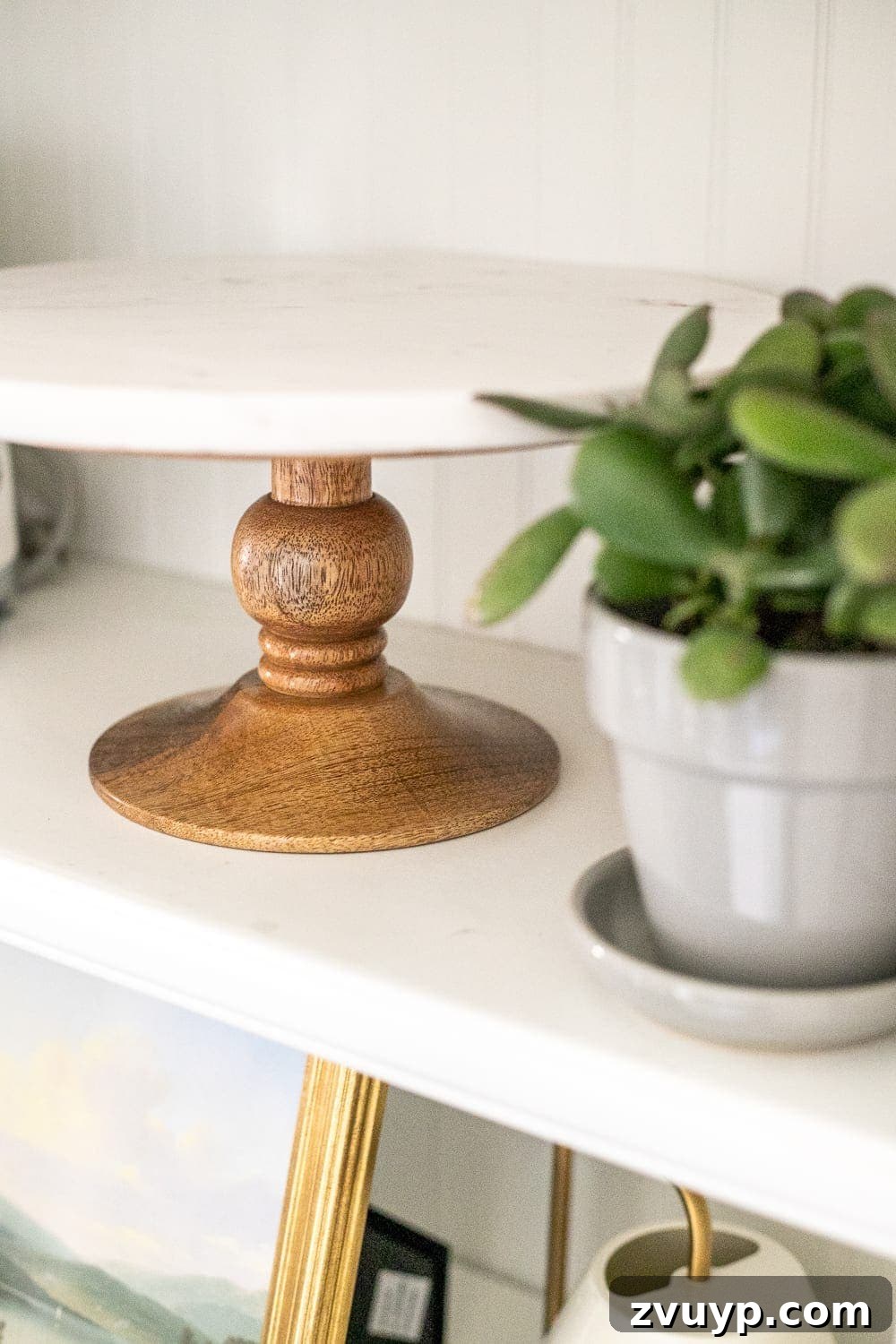 Simple Ways to Style Your Shelves 15 A decorative cake stand and cookbooks are neatly arranged on a kitchen shelf.