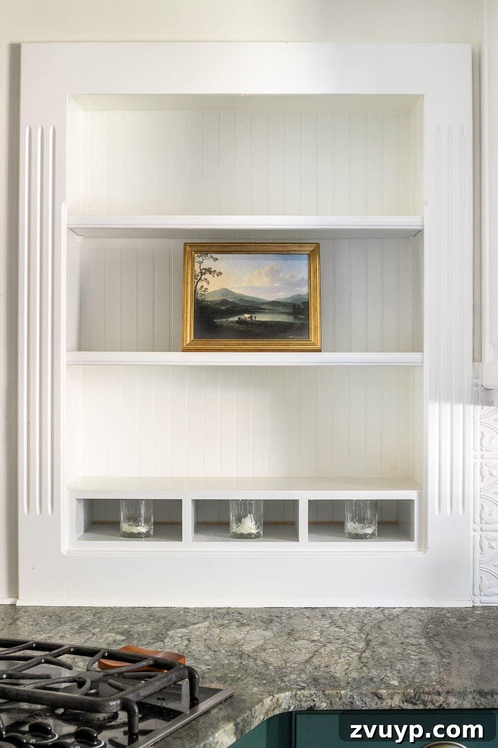 Simple Ways to Style Your Shelves 4 A vintage-style oil landscape art in a gold frame serves as a focal point on a kitchen shelf.