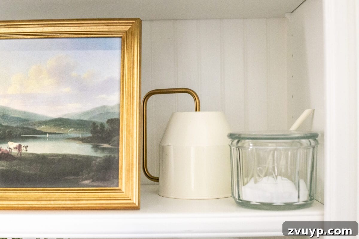 Simple Ways to Style Your Shelves 10 A mix of large and small decorative elements, including a cake stand and a small plant, on a styled shelf.