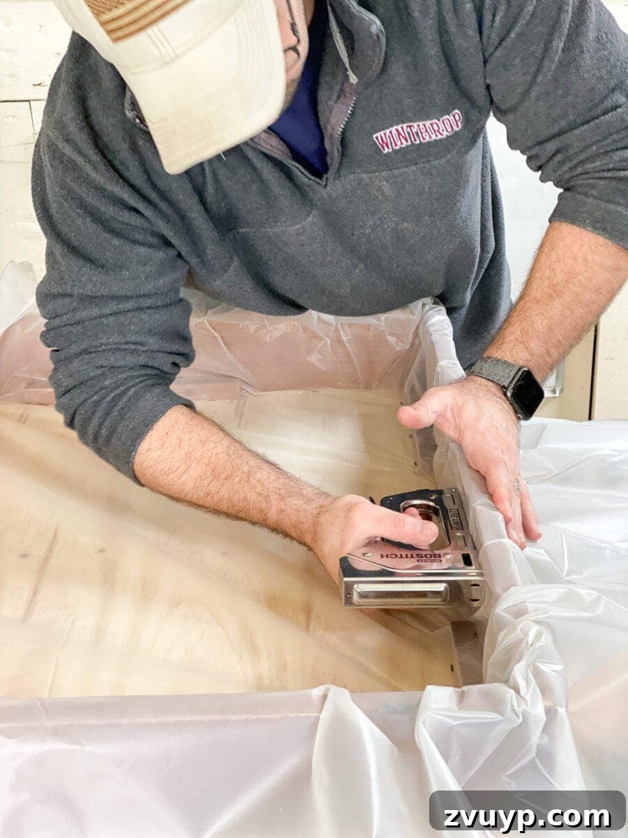 Craft a Vertical Garden from Reclaimed Wood 12 Securing the plastic drop cloth liner inside the wooden planter frame with a heavy-duty stapler, ensuring waterproofing.