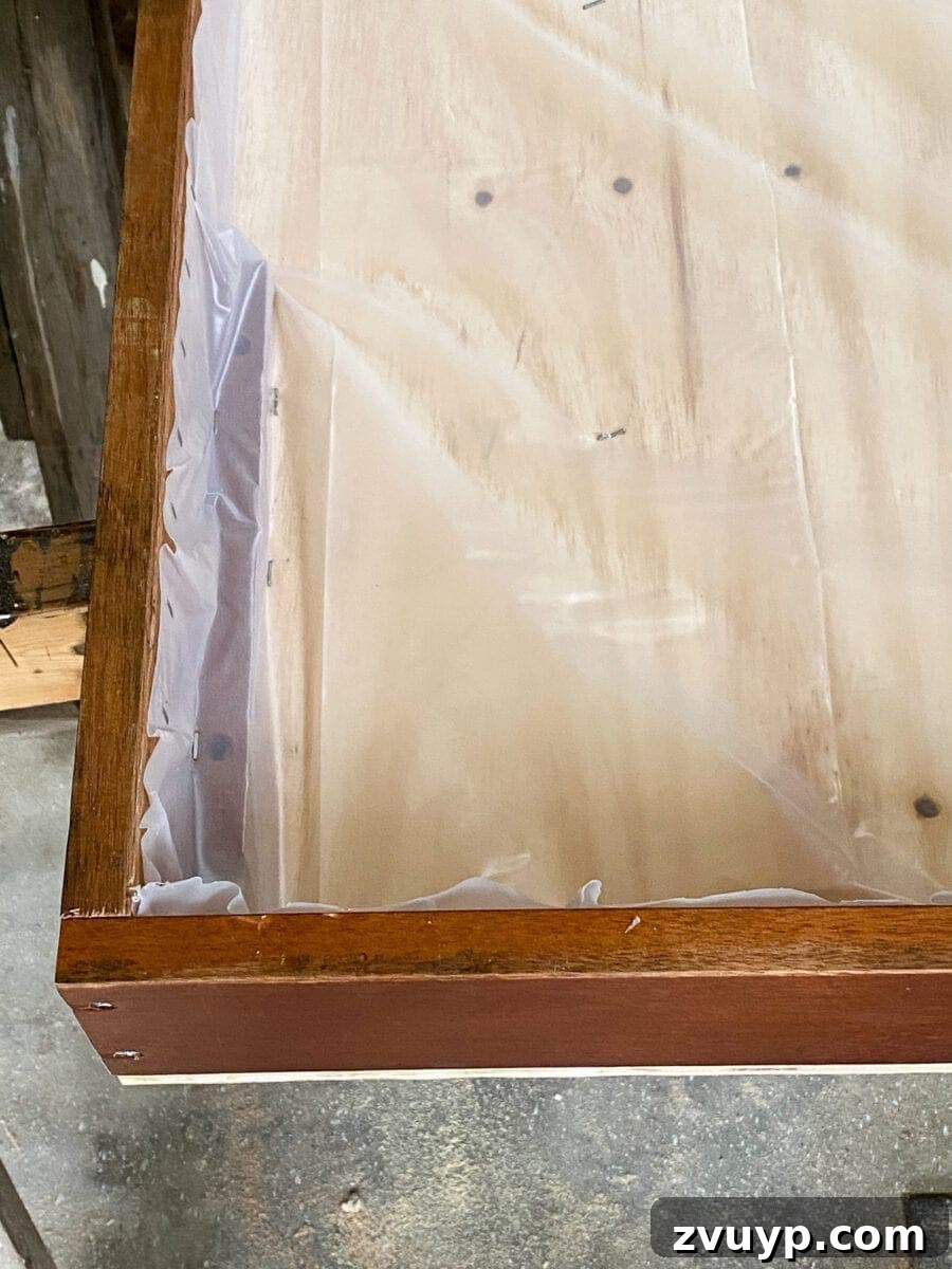 Craft a Vertical Garden from Reclaimed Wood 13 Trimming excess plastic liner with scissors, creating a neat finish inside the wooden wall planter.