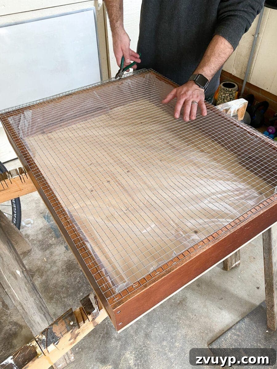 Craft a Vertical Garden from Reclaimed Wood 15 Trimming excess hardware cloth with wire snips and flattening sharp edges with a hammer for a safe and neat finish on the vertical planter.