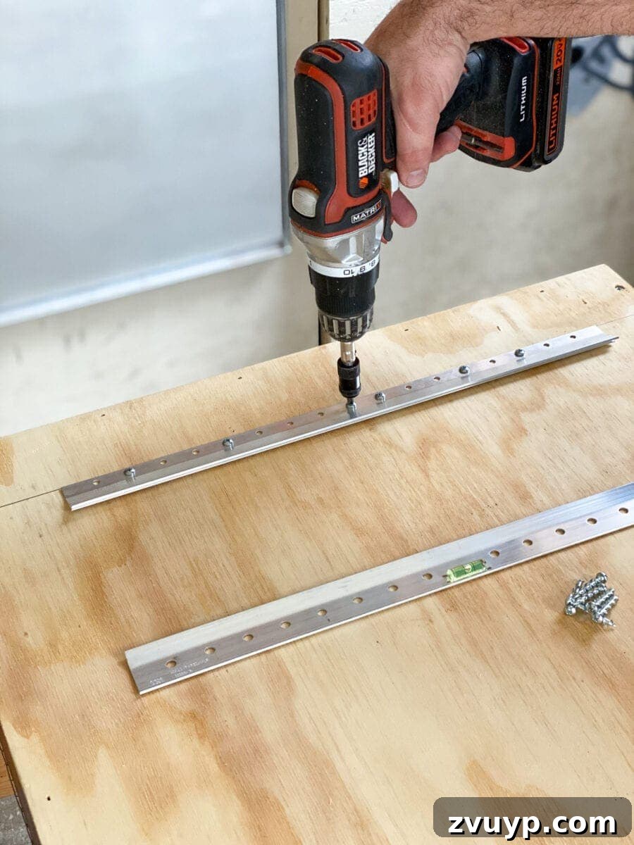 Craft a Vertical Garden from Reclaimed Wood 16 Attaching a Hangman hanger to the plywood back of the vertical wall planter, preparing it for secure wall mounting.