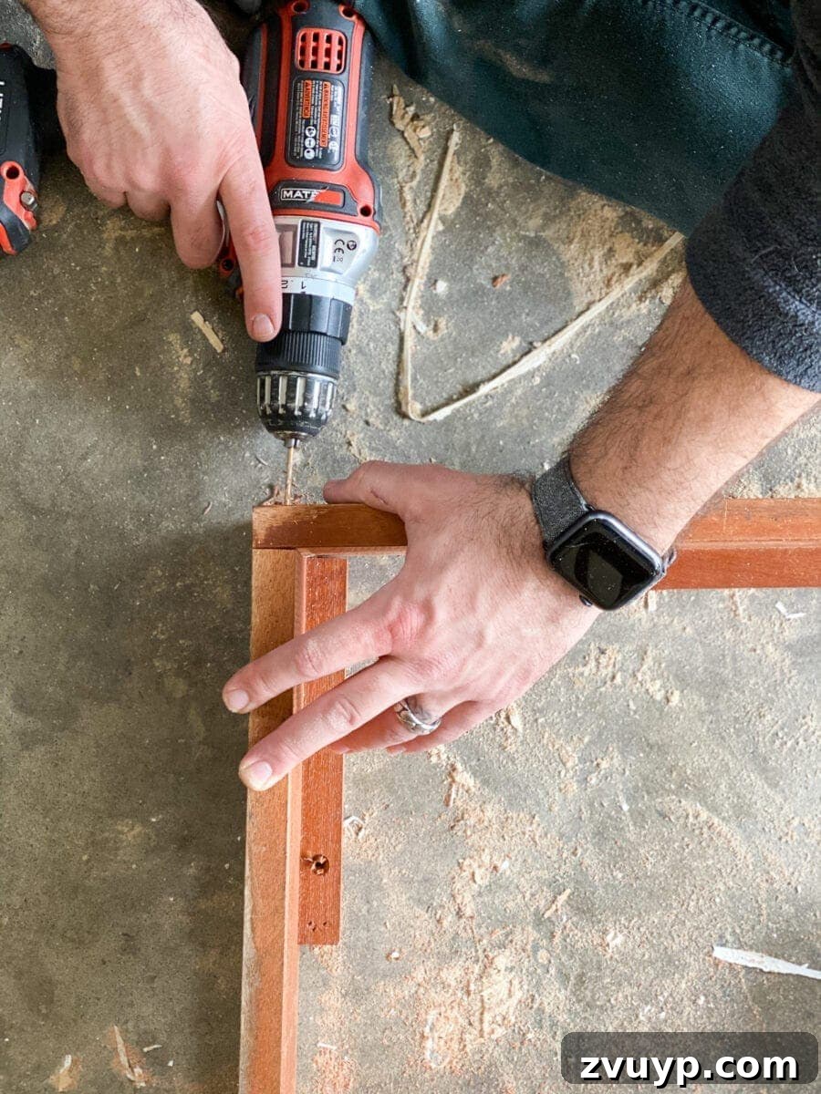 Craft a Vertical Garden from Reclaimed Wood 8 Assembling the wooden frame for a vertical planter, using a power drill to secure corners with wood screws.