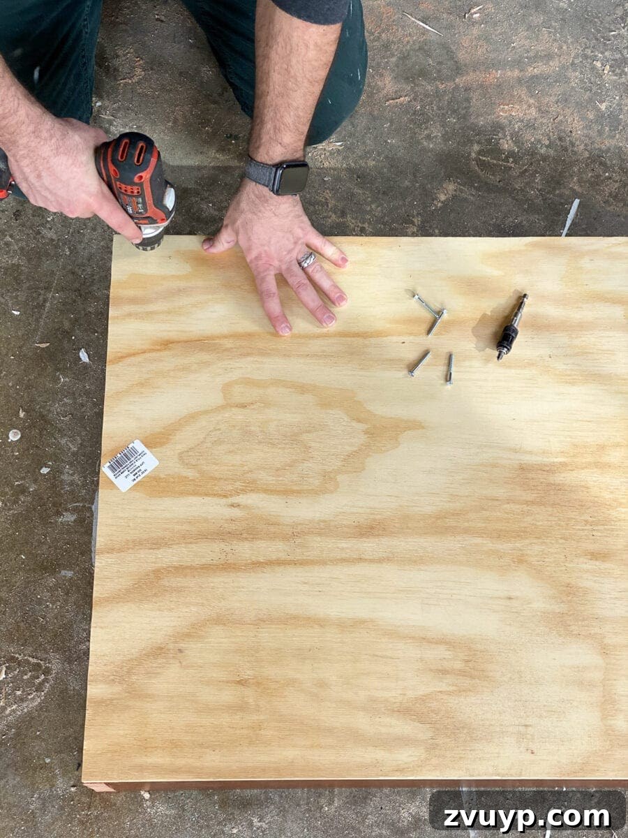 Craft a Vertical Garden from Reclaimed Wood 9 Attaching the plywood back panel to the assembled wooden frame of the DIY wall planter using wood screws.