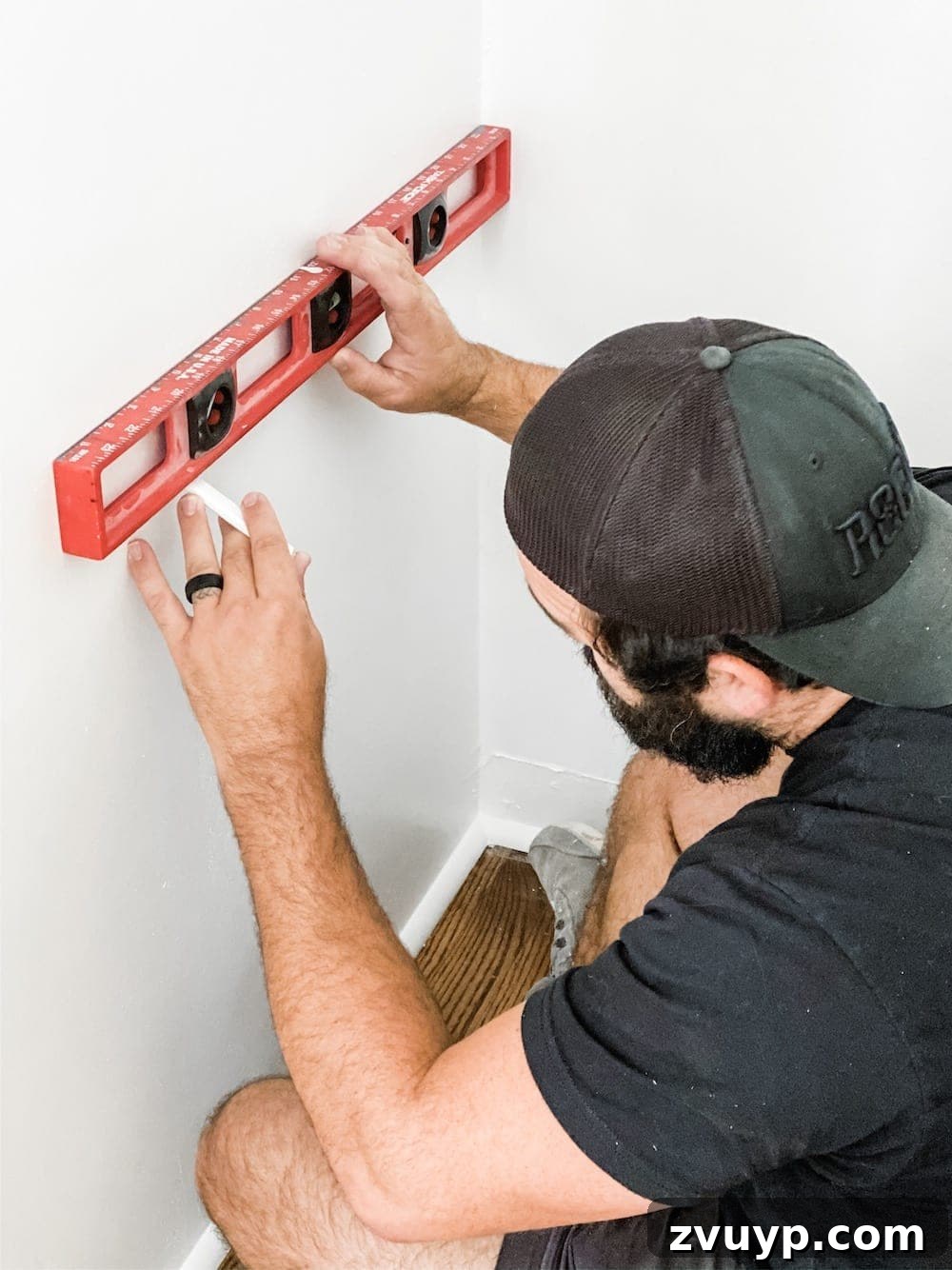 Person using a level and marking stud locations on a wall for shelf installation
