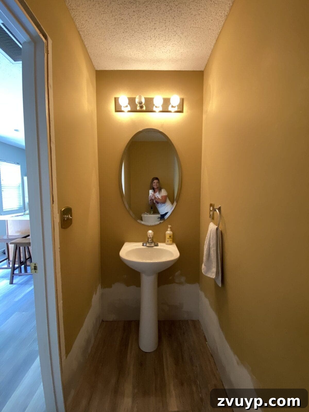 Golden State Powder Room Serenity 4 Before photo of a small powder room with dated gold walls and a simple mirror