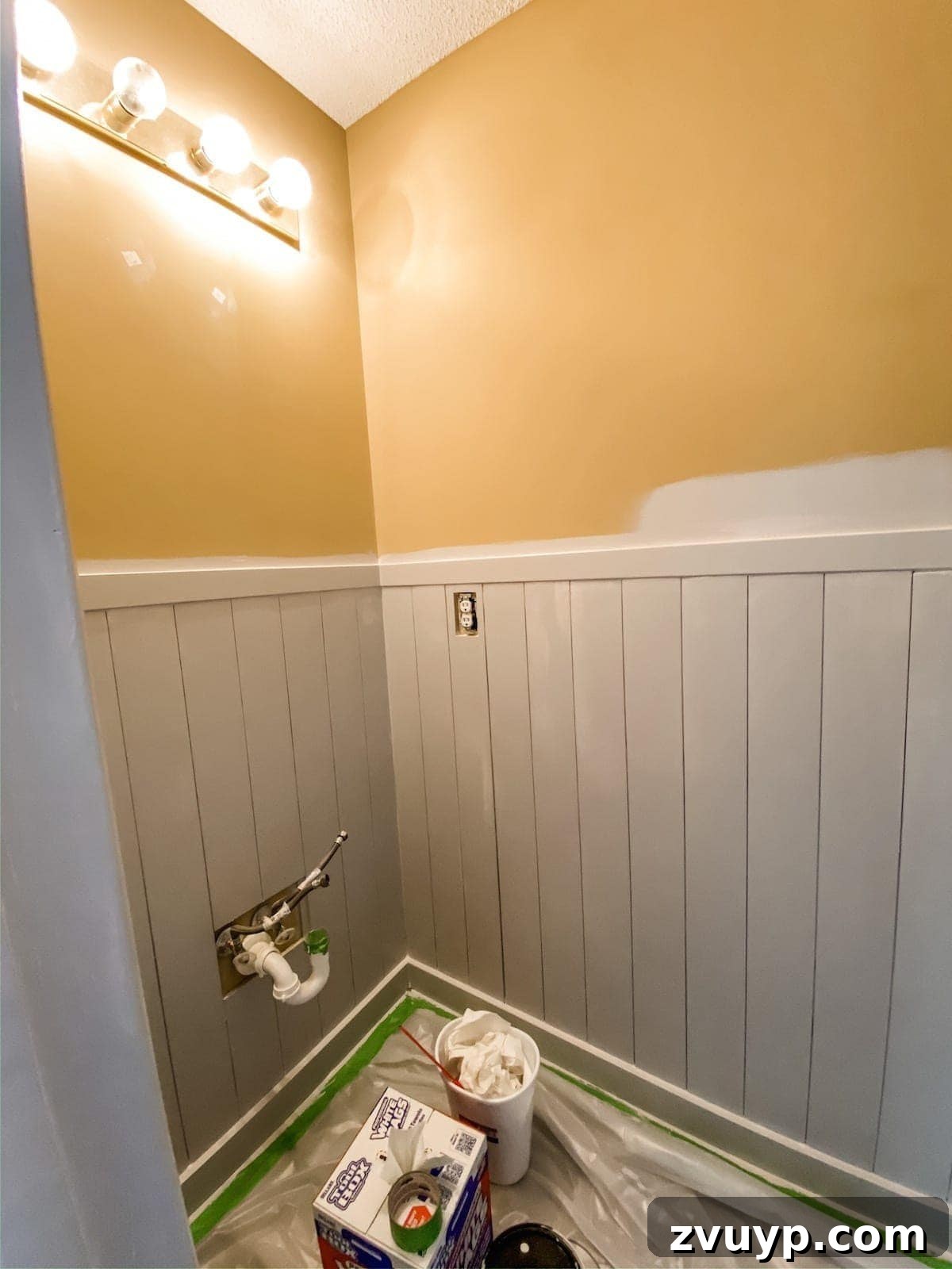 Effortless Bathroom Makeover: DIY Vertical Shiplap Wainscoting 17 Painting vertical shiplap wainscoting in a bathroom with a roller and brush.