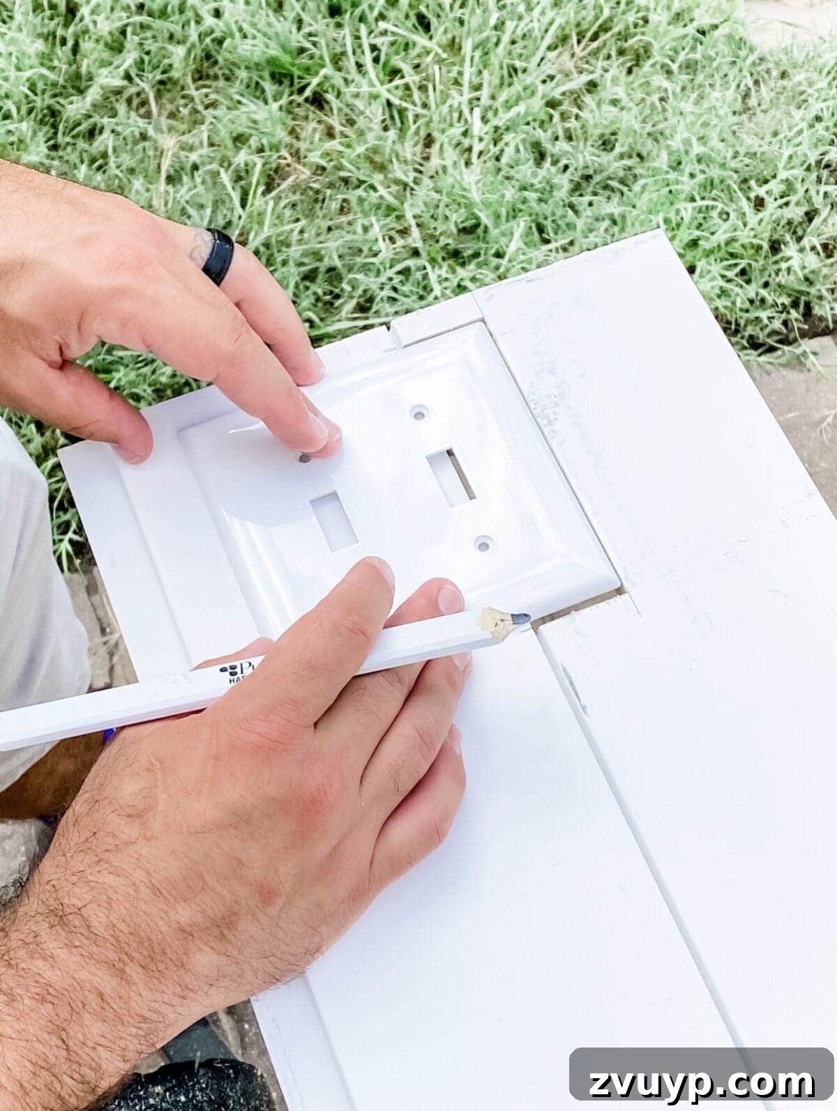 Effortless Bathroom Makeover: DIY Vertical Shiplap Wainscoting 8 Tracing an outlet cover onto a shiplap board for precise cutting.