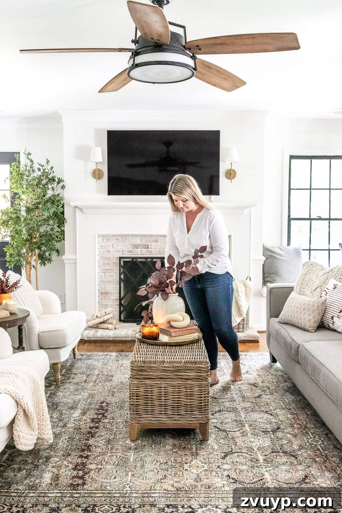 An Earthy Fall Living Room and My Go-To Budget Fall Decor Capsule 2 Cozy living room decorated for fall with warm earthy tones, cable knit throws, and a vintage-style rug, featuring a ceiling fan and TV above the fireplace.