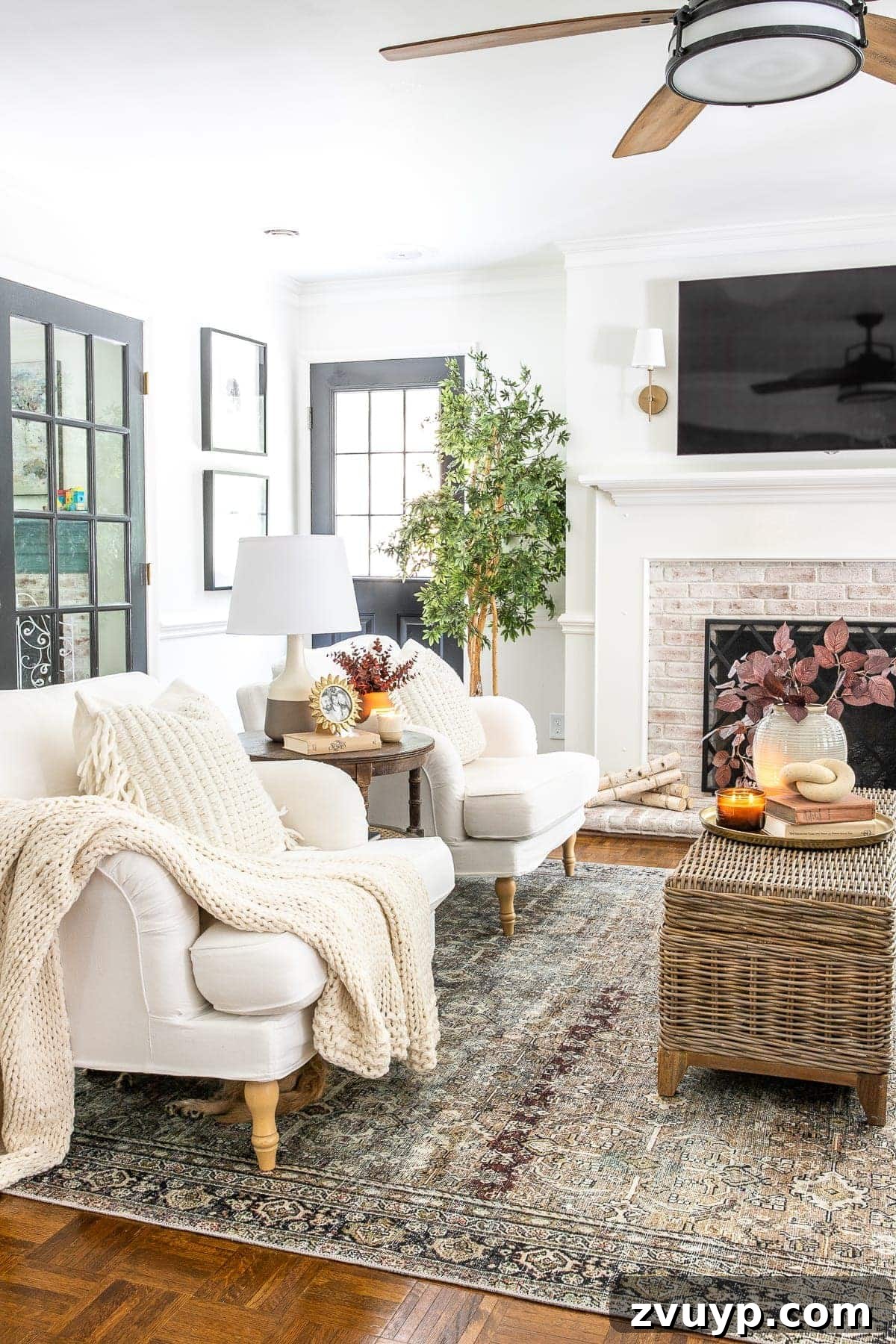 An Earthy Fall Living Room and My Go-To Budget Fall Decor Capsule 10 Spacious living room beautifully decorated for fall, featuring a rust and olive vintage-style rug, a ceiling fan, and a TV mounted above the fireplace.