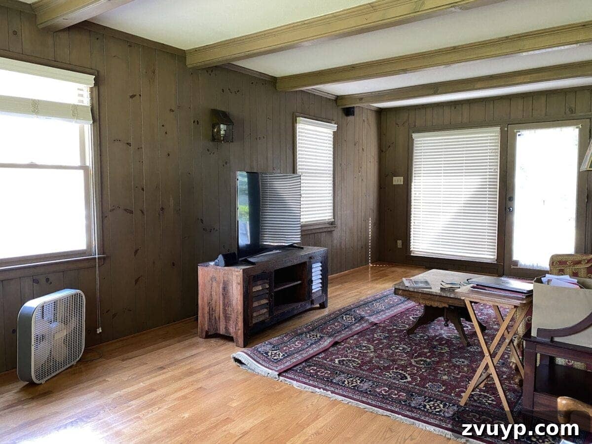 McNay Home Modern Coastal Living Revealed 2 Before image of a living room with prominent wooden beams and planked walls, showing potential for a modern coastal design