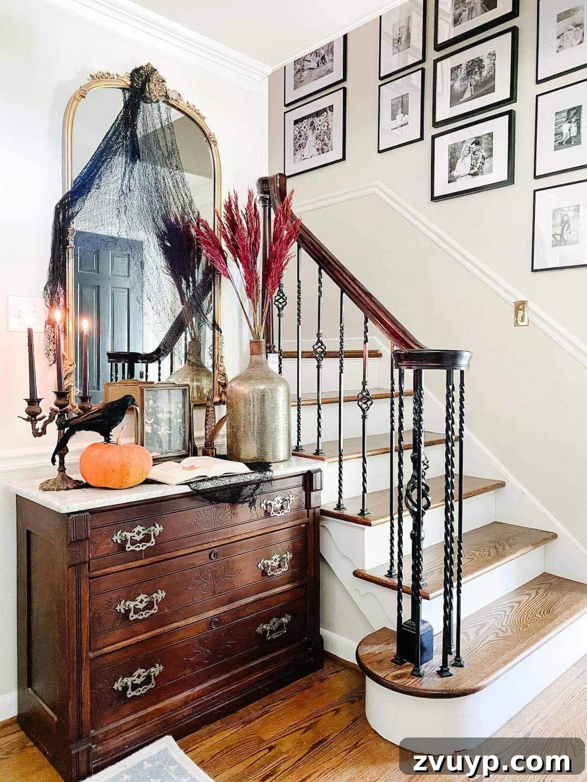 Conjuring Classic Chills: 10 Vintage Halloween Prints for Your Entryway 2 A stylish entryway decorated for fall and vintage Halloween, featuring antique portraits in ornate frames, a candelabra, and autumnal accents.