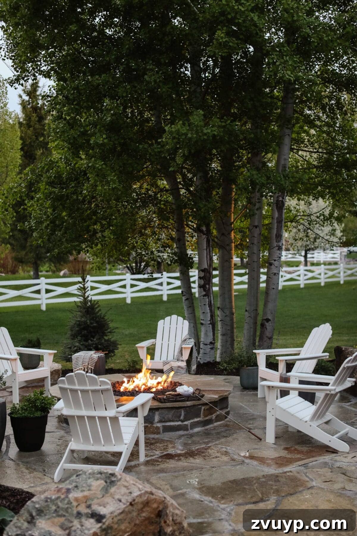 Elevate Your Outdoor Space: 15 Stunning Fire Pit Designs 11 Inviting backyard fire pit area with comfortable Adirondack chairs set on elegant stone pavers.