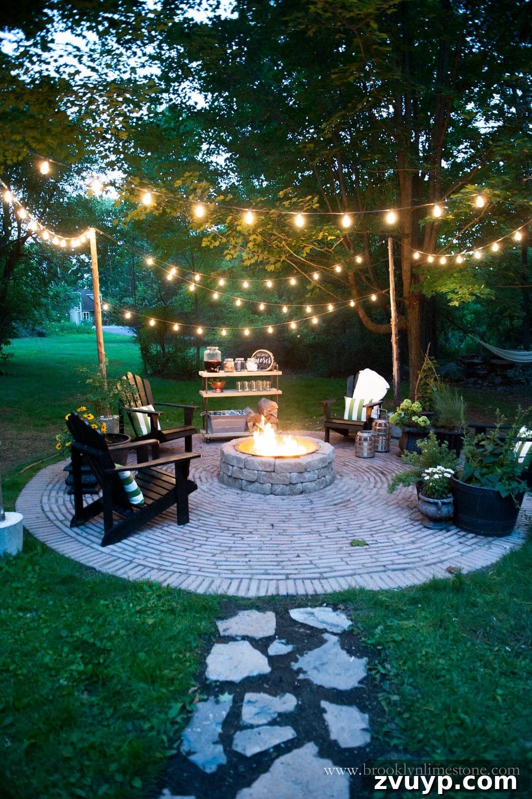 Elevate Your Outdoor Space: 15 Stunning Fire Pit Designs 16 Inviting fire pit area adorned with ambient string lights and a well-defined stone walkway, accessorized with decor.