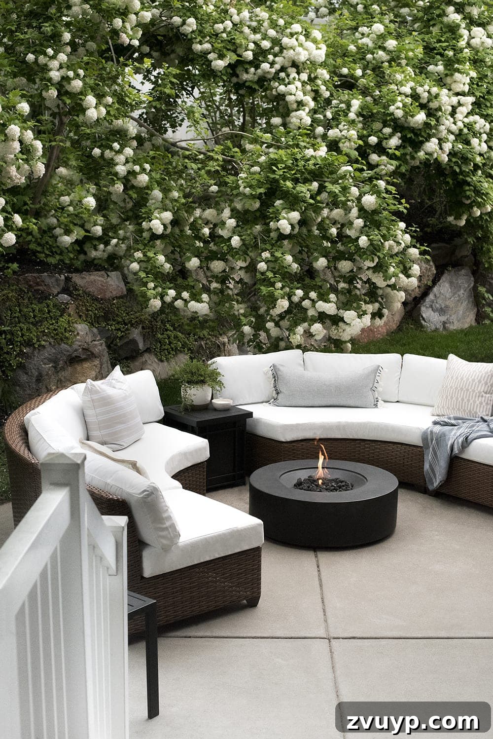 Elevate Your Outdoor Space: 15 Stunning Fire Pit Designs 10 Elegant back patio fire pit surrounded by comfortable curved sectionals and vibrant flowering trees.