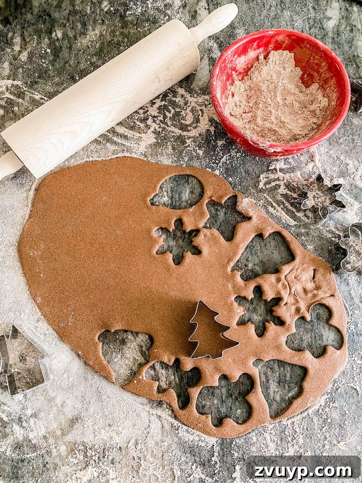 Craft Your Own Cinnamon Salt Dough Decorations 10 Rolling out cinnamon salt dough and cutting various holiday shapes with cookie cutters on a floured surface for ornaments.