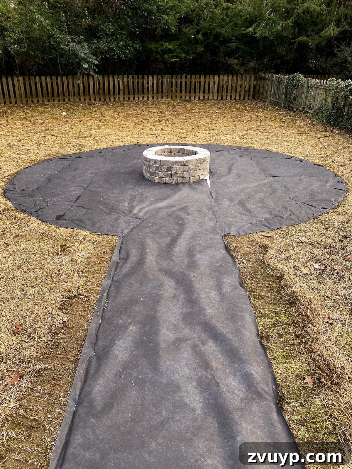 Weekend Wonder: DIY Pea Gravel Fire Pit 16 Laying and securing landscape fabric around the designated fire pit area to prevent weed growth.