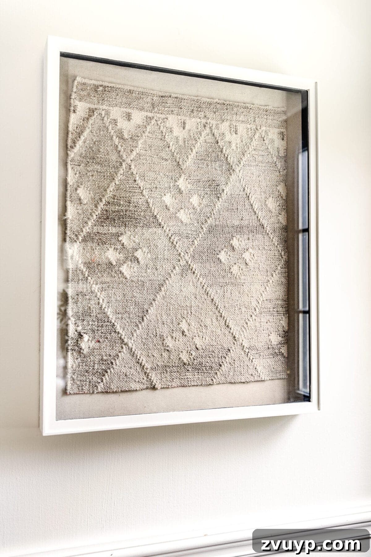 Close-up of DIY textile art made from a recycled rug, featuring abstract textures in a shadow box frame.