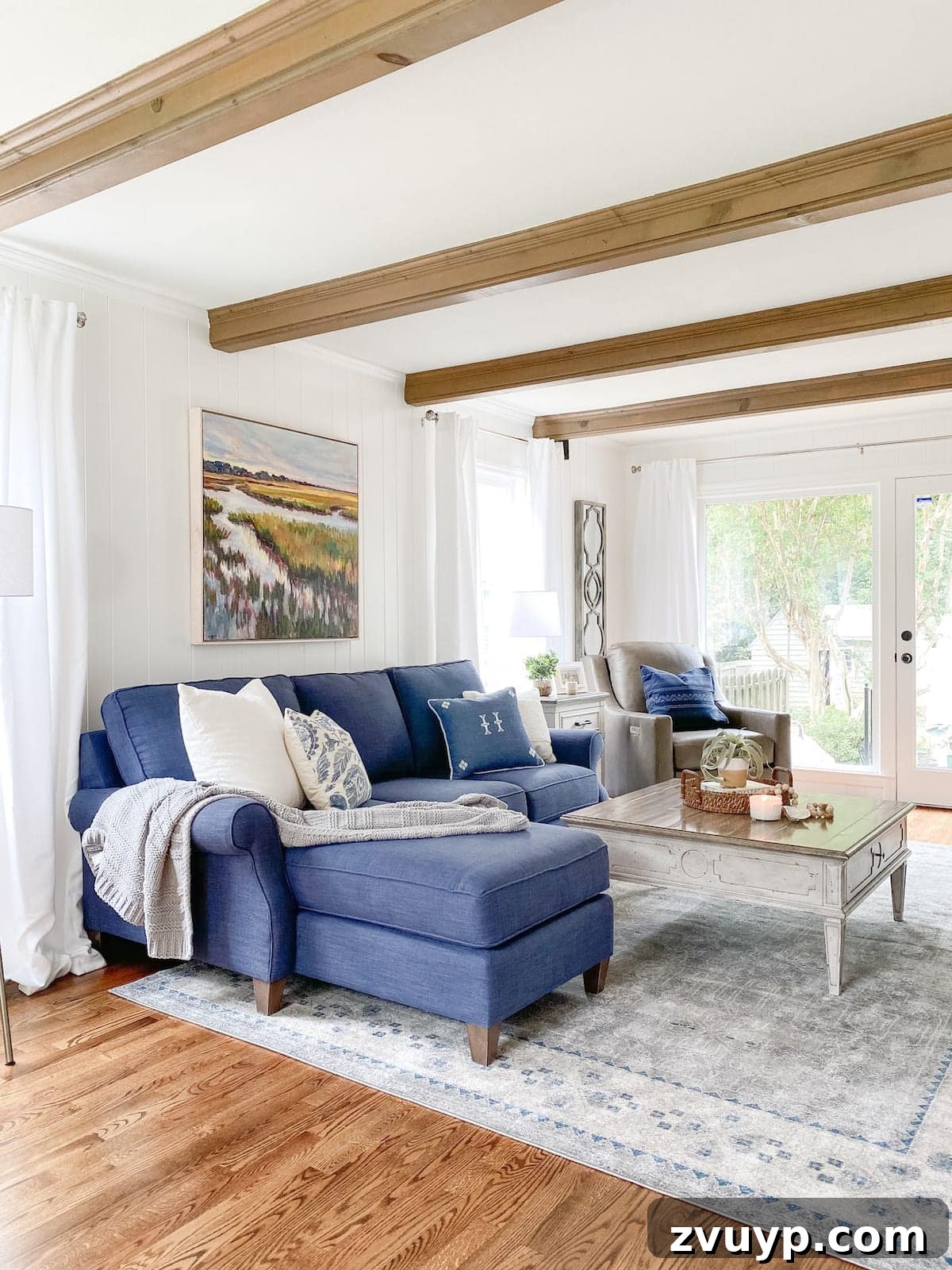 Your Blueprint for Choosing the Ideal Rug 11 coastal living room with beams, navy sofa, rug, and weathered table