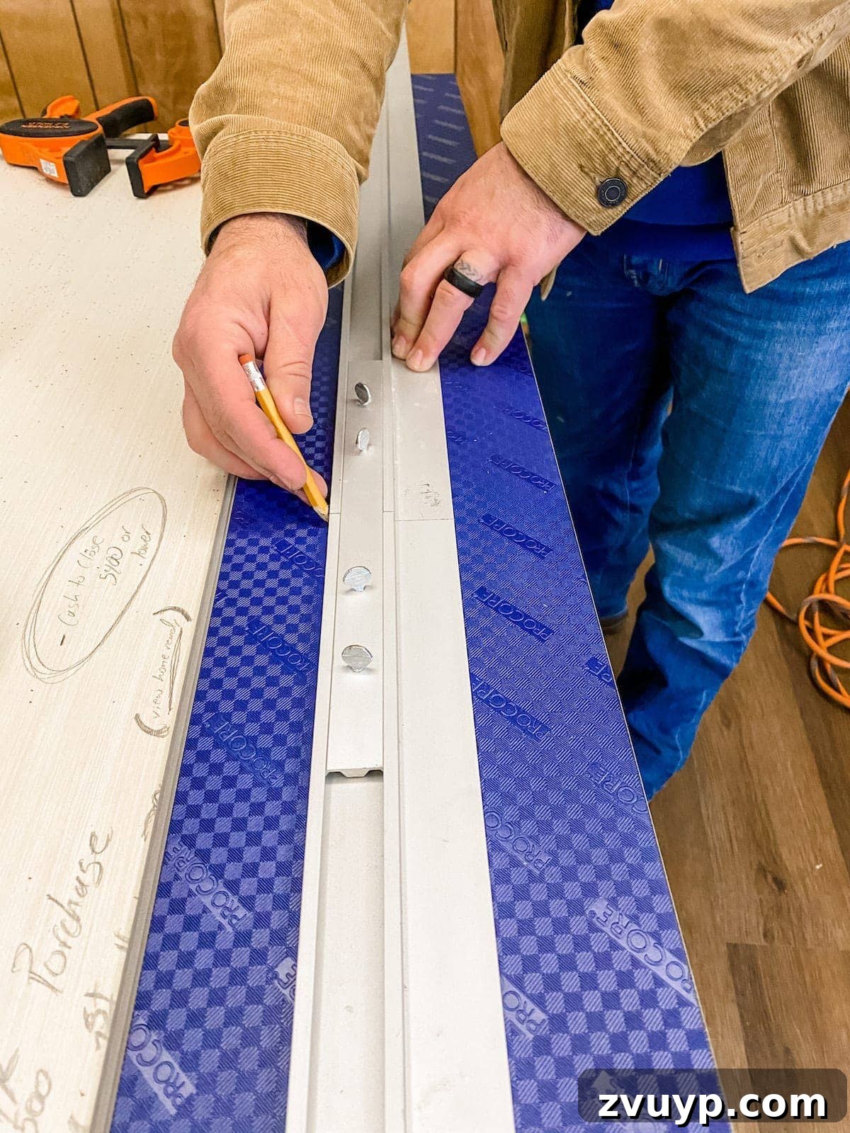 Using a straight edge to score and cut luxury vinyl plank flooring with a utility knife