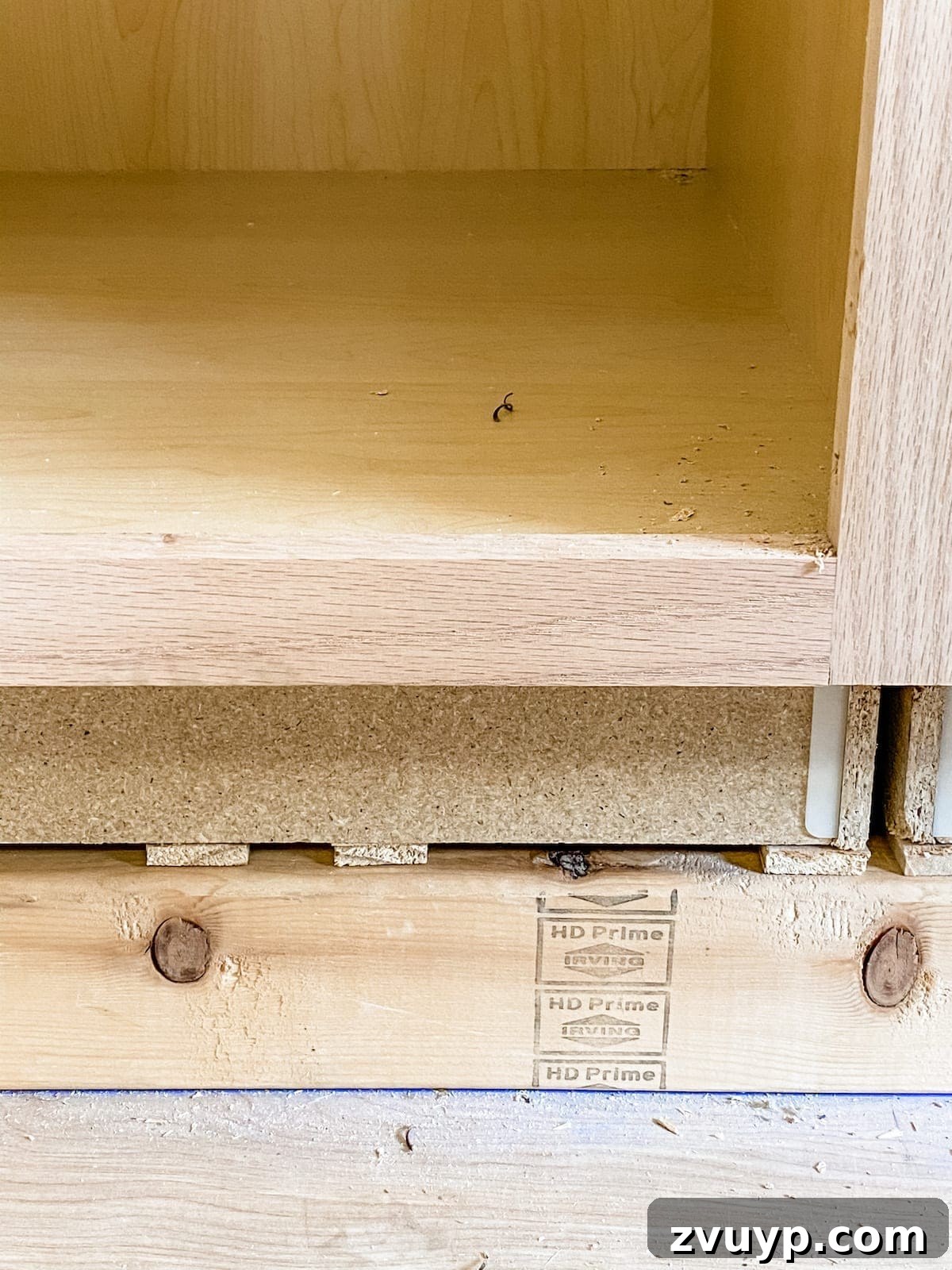 DIY Custom Built-In Storage and Window Nook 14 Close-up of wood shims under a cabinet for leveling purposes