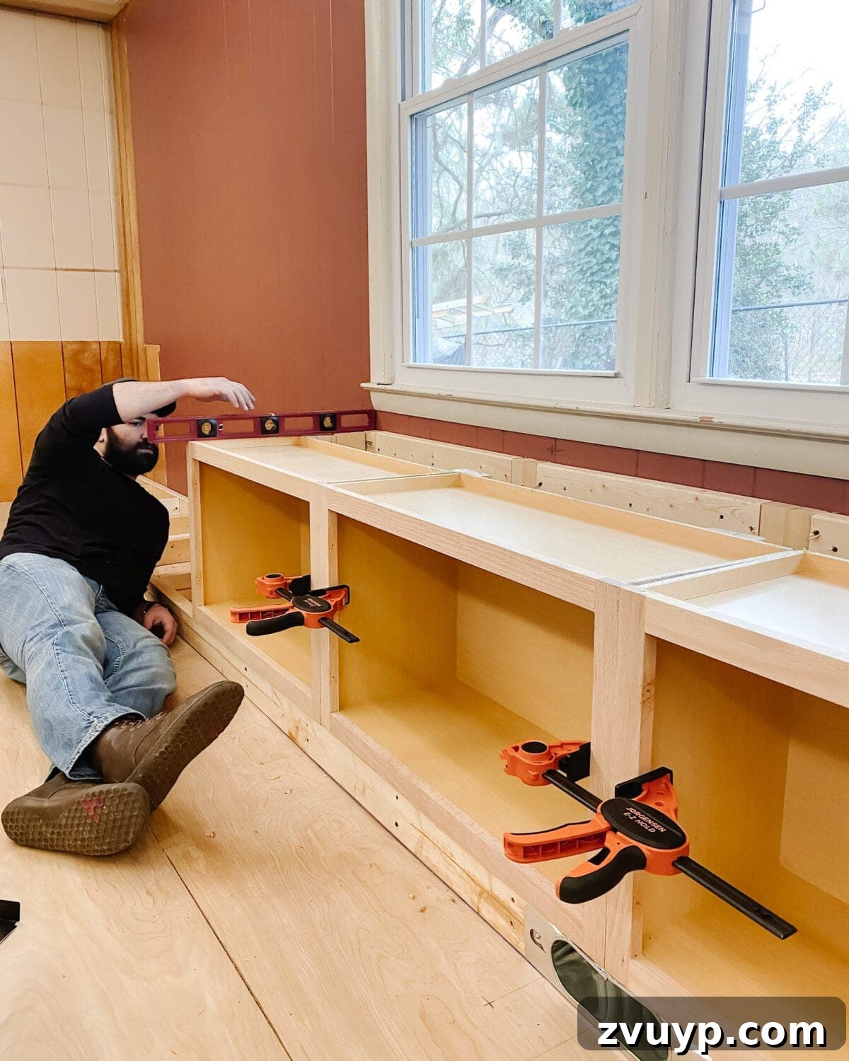 DIY Custom Built-In Storage and Window Nook 17 Checking the level of the installed window seat cabinets before adding the top