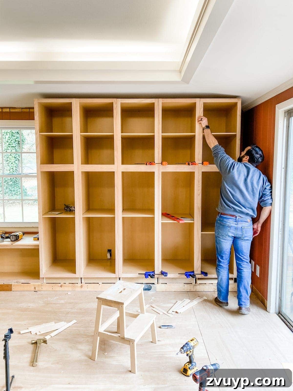 DIY Custom Built-In Storage and Window Nook 21 Installation of multiple tall pantry cabinets on the right side of the window seat, showing alignment