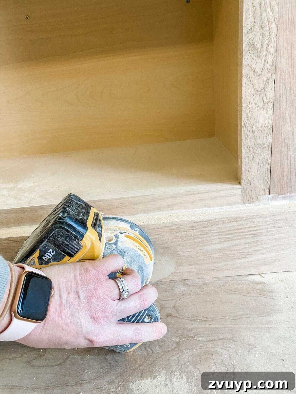 DIY Custom Built-In Storage and Window Nook 32 Orbital sander smoothing wood filler on the built-in cabinet trim