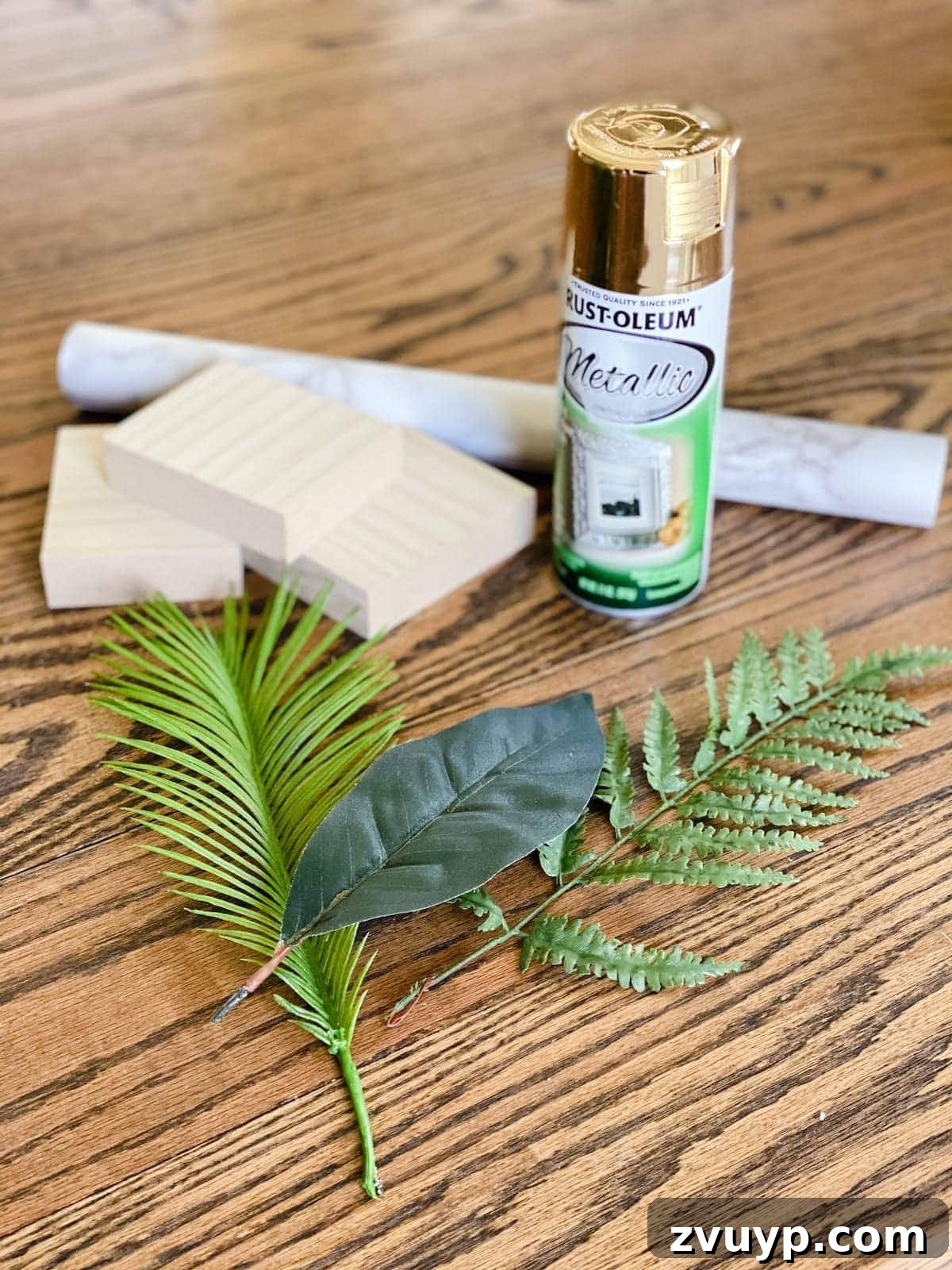 DIY Gold Leaf Sculpture: Luxury for Less 3 Supplies for making a DIY gold leaf sculpture, including faux leaves, gold spray paint, scrap wood, and marble contact paper.