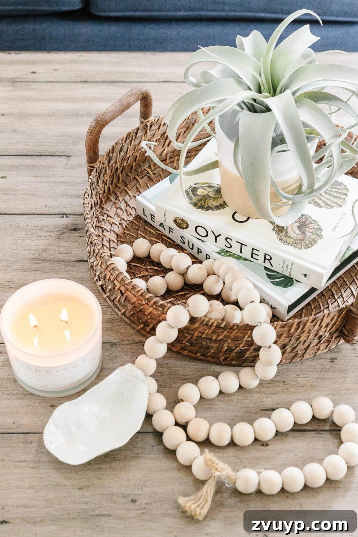 Simple Steps to a Stunning Coffee Table 5 Coastal style coffee table decor featuring a rattan tray, wooden beads, air plant, and curated books