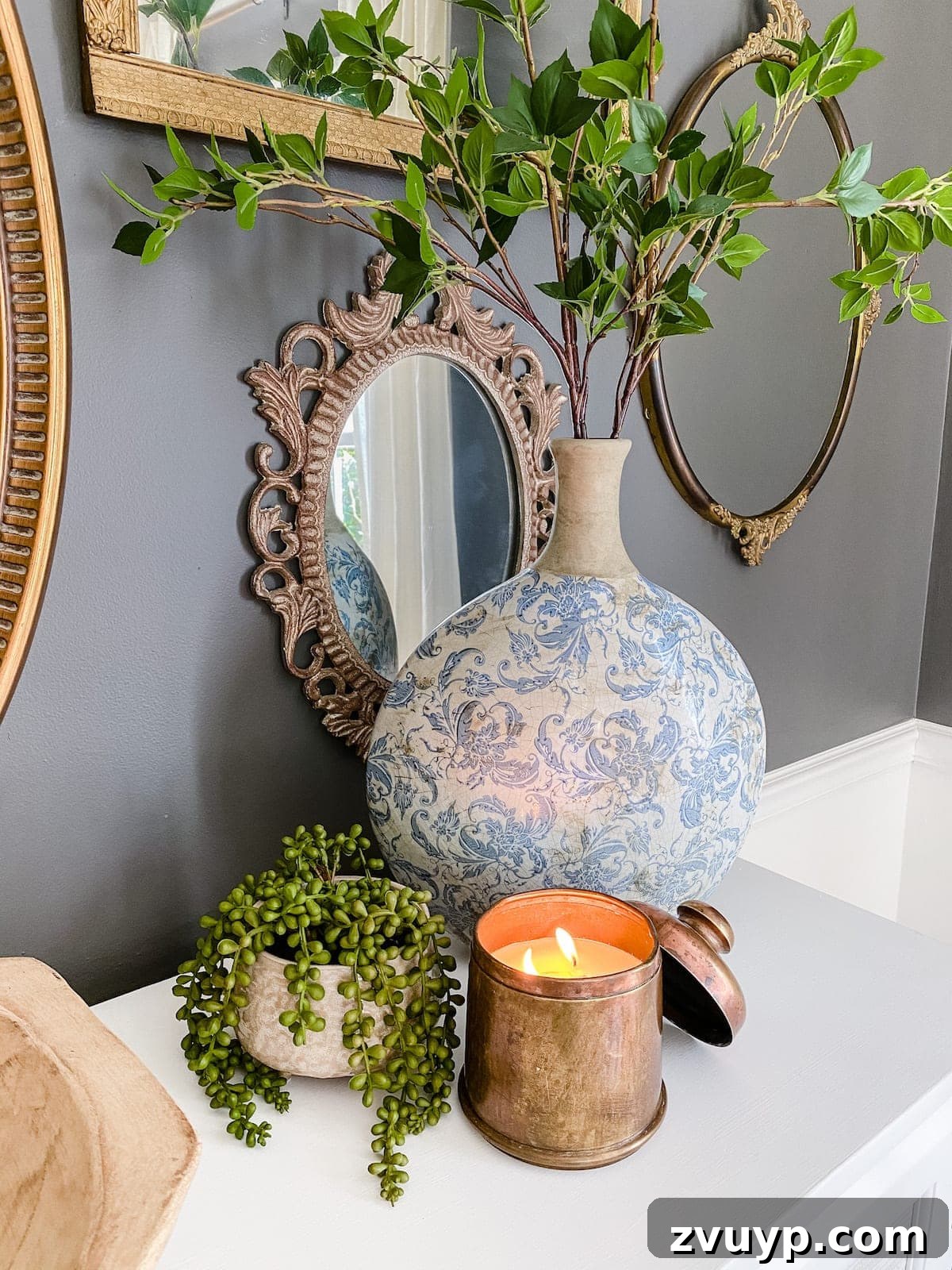 Transforming Thrifted Brass into Elegant Candles 10 Styled image of the antique brass canister candle with a Chinoiserie vase and greenery, highlighting its decorative appeal.