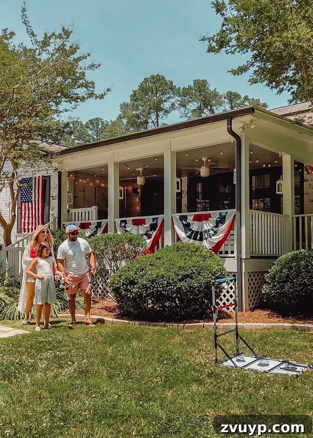 Crowd-Pleasing Yard Games for Every Backyard Cookout 2 family playing a yard game at a backyard barbecue decorated for July 4th.