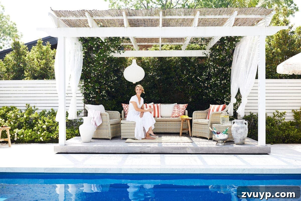 7 Pool Cabana Ideas for Your Backyard Oasis 8 A picturesque pool cabana with flowing white gauze curtains and elegant rattan outdoor furniture, creating a serene and airy atmosphere.