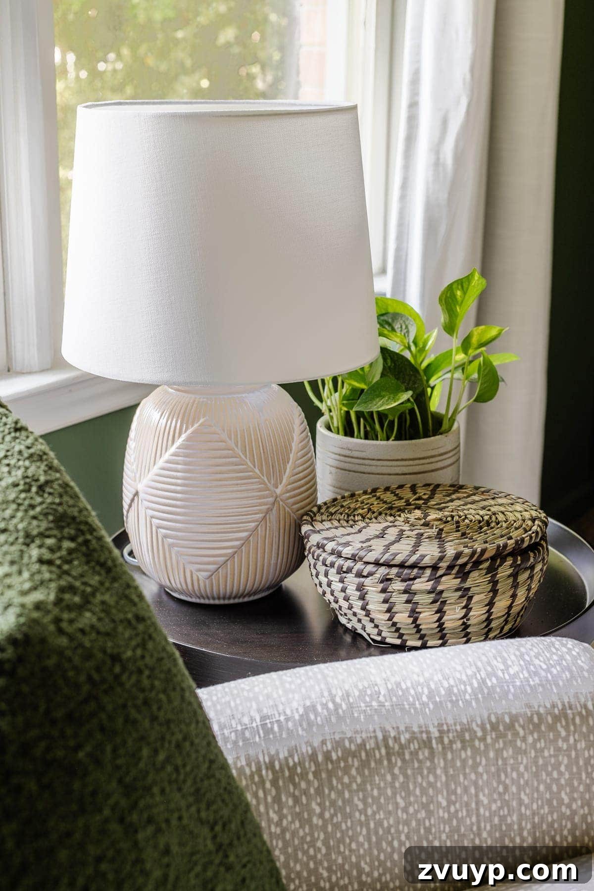 Little Explorer's Woodland Nursery Transformation 12 A serene nursery side table styled with a reactive glaze lamp, a vibrant plant, and a lidded basket for discreet baby essentials.