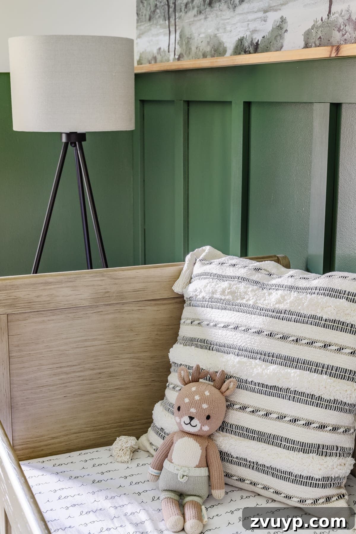 Little Explorer's Woodland Nursery Transformation 16 A cozy baby boy nursery with a woodland theme, featuring a floor lamp, a striped pillow, and a natural wood crib.