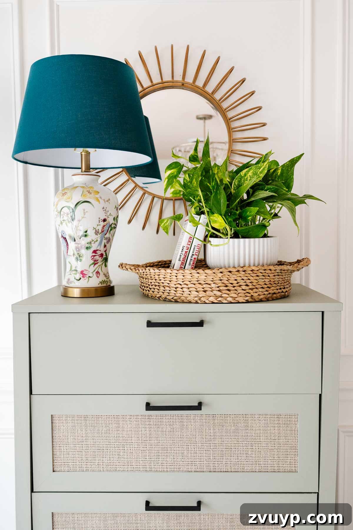 Regan's Room Transformation Painting Laminate Furniture 11 Stylishly arranged decor on top of a newly painted dresser, featuring a sunburst mirror and a green plant in a fluted planter.