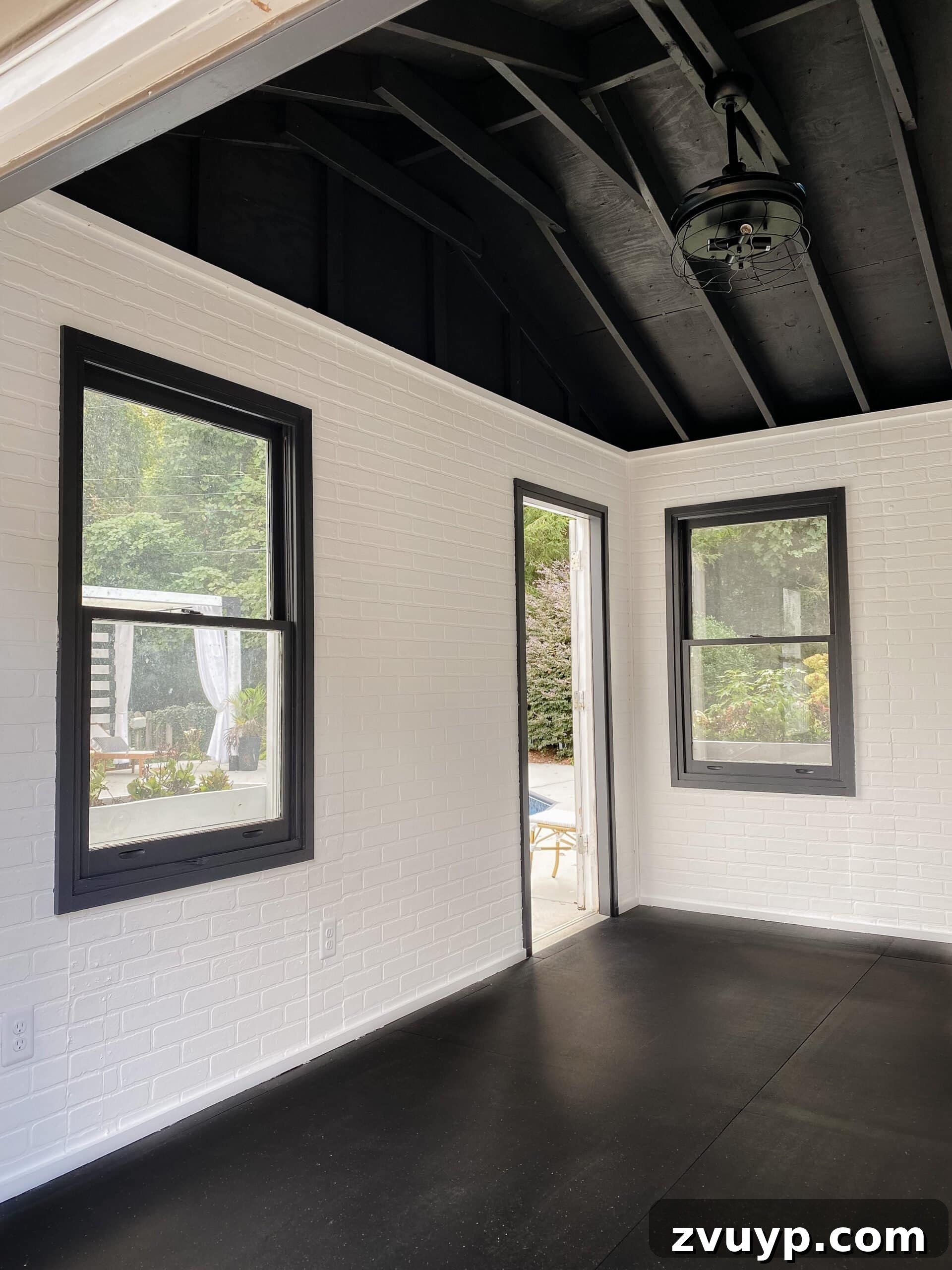 Transform Your Gym Shed with DIY Faux Brick Walls 4 After photo of the renovated gym shed featuring bright white faux brick wall panels, a dramatic black ceiling, and ample natural light, showing a modern and spacious feel.