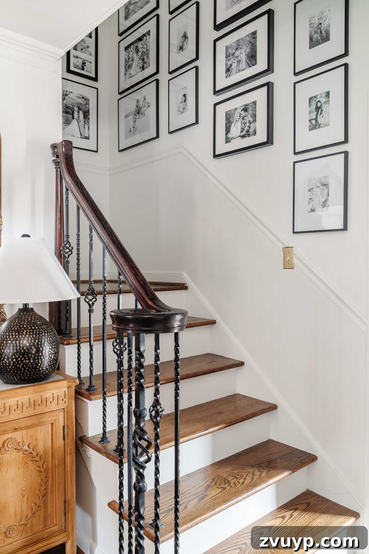 Vintage Meets Modern Foyer Makeover 13 Stylish stairway gallery wall featuring an array of black frames with black and white family photos, creating a cohesive and timeless display of cherished memories.