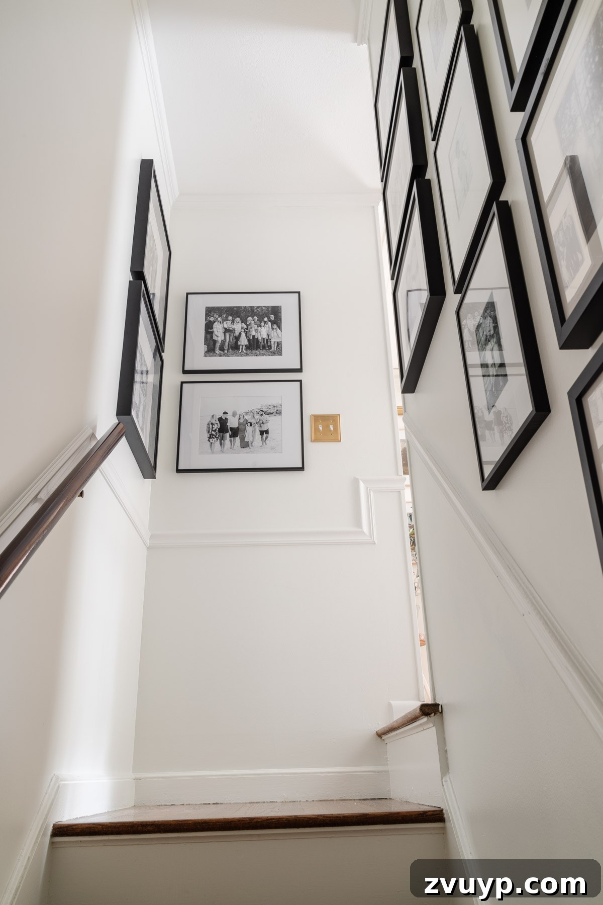 Vintage Meets Modern Foyer Makeover 16 A grand family stairway gallery wall featuring an extensive collection of framed black and white photographs, creating an impressive and sentimental display along the staircase.