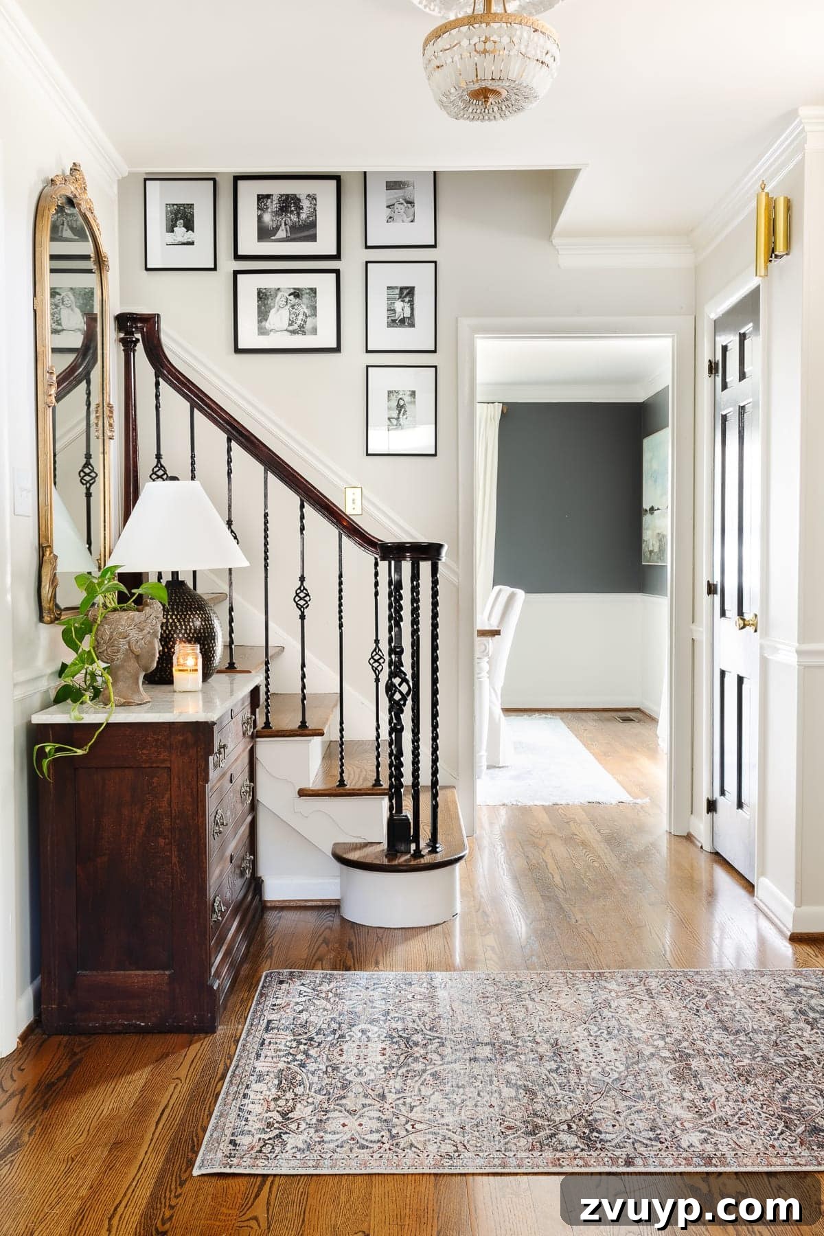 Vintage Meets Modern Foyer Makeover 3 A beautifully decorated foyer showcasing an elegant entryway table, a textured rug, and a captivating stairway gallery wall, creating a personalized and inviting atmosphere.