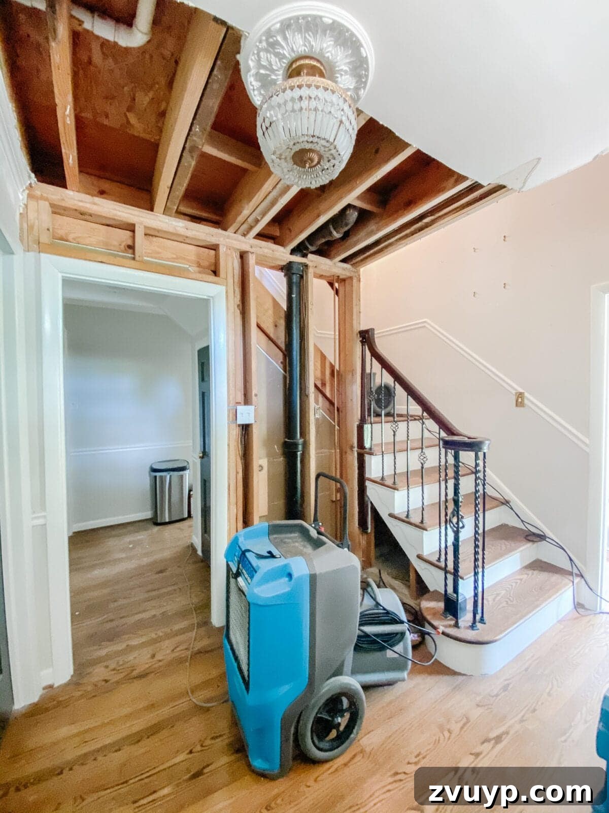 Vintage Meets Modern Foyer Makeover 6 Image showing the initial stages of water mitigation in a foyer, with professional equipment and exposed walls after water damage.