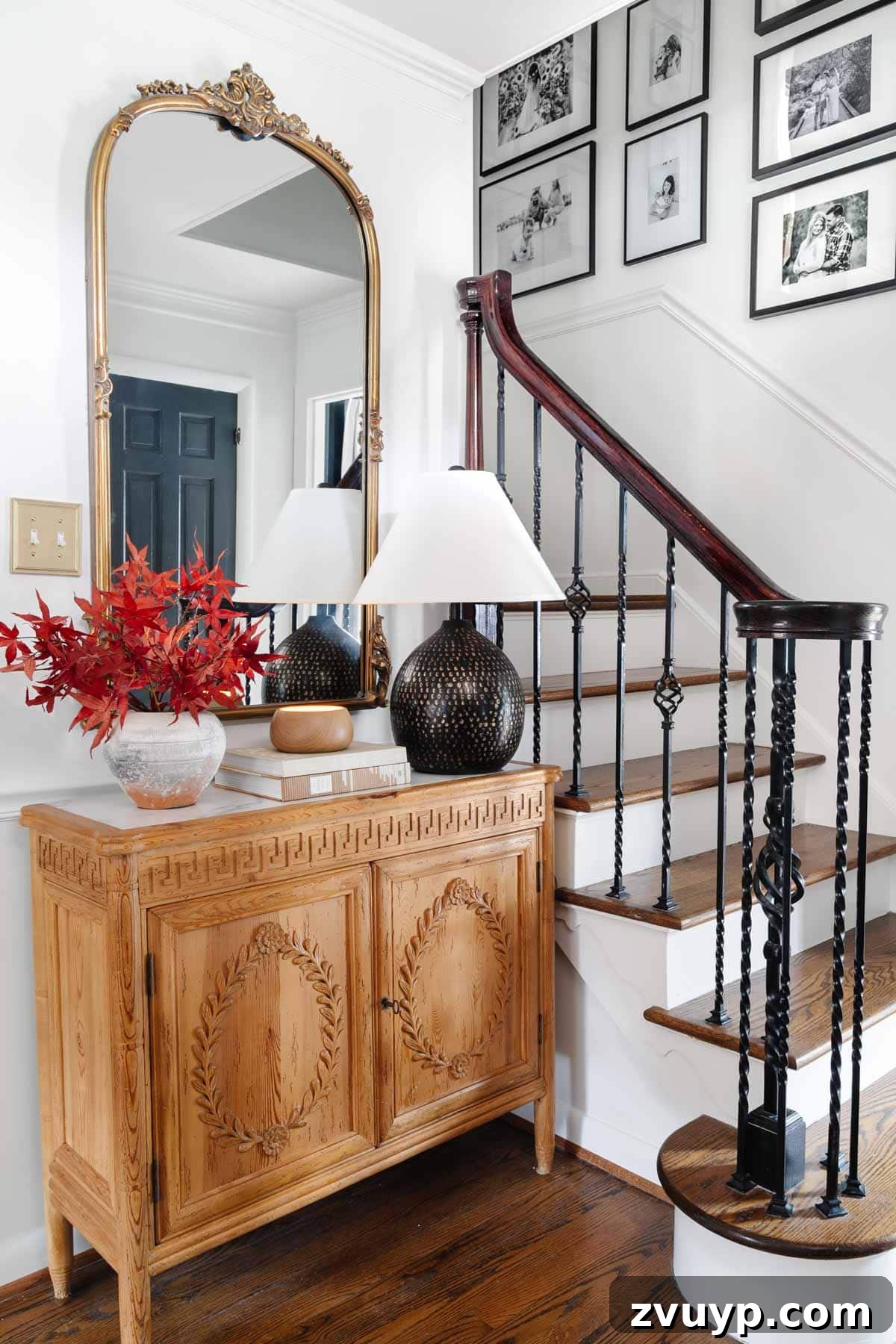 Vintage Meets Modern Foyer Makeover 8 Charming foyer table vignette featuring an elegant lamp, a classic mirror reflecting natural light, and a vase filled with vibrant fall leaves, creating a cozy autumn ambiance.