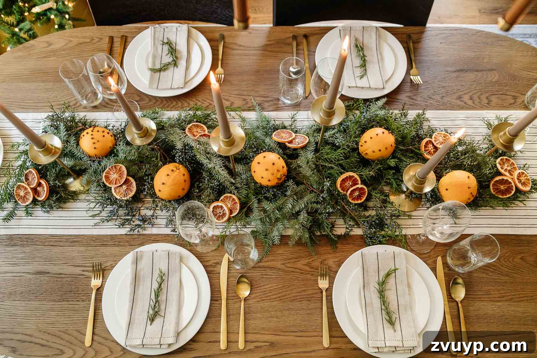 Elegant Christmas Tablescapes for Less 2 Simple and inexpensive vintage Christmas table centerpiece idea featuring fresh-cut evergreen branches, juniper berries, dried orange slices, aromatic orange pomanders, and elegant gold candle holders