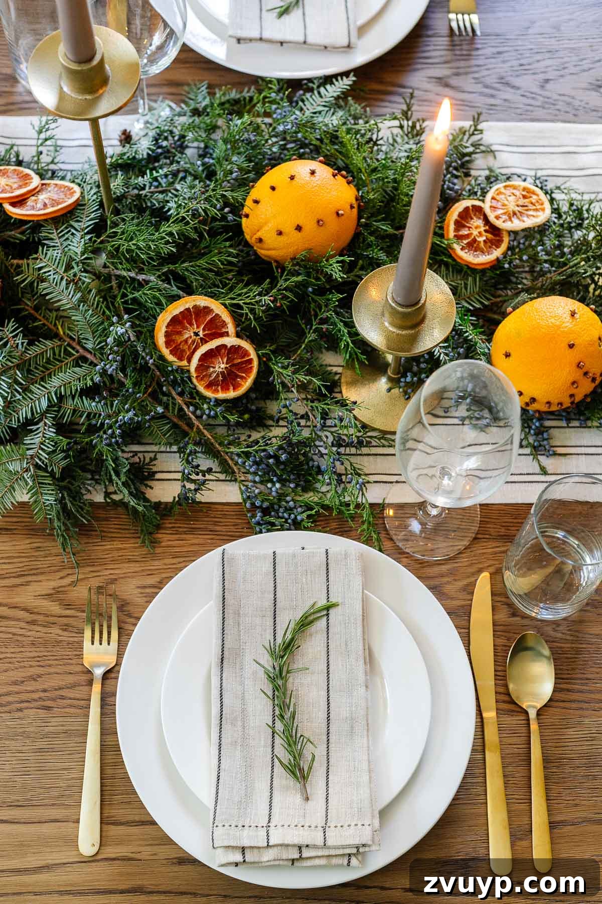 Elegant Christmas Tablescapes for Less 7 Elegant Christmas place setting featuring a sprig of fresh rosemary on a napkin, complementing the natural table centerpiece